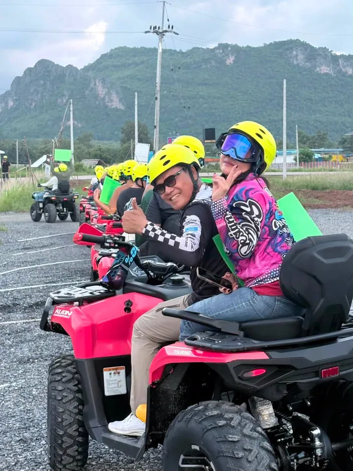 กรุ๊ปลูกค้าสวมหมวกกันน็อคนั่งบนรถ ATV ก่อนออกตัว มีแนวเขาเป็นฉากหลัง