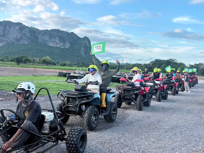กลุ่มลูกค้าบนรถ ATV เรียงแถวโบกมือทักทาย ฉากหลังเป็นแนวเขาหินปูน