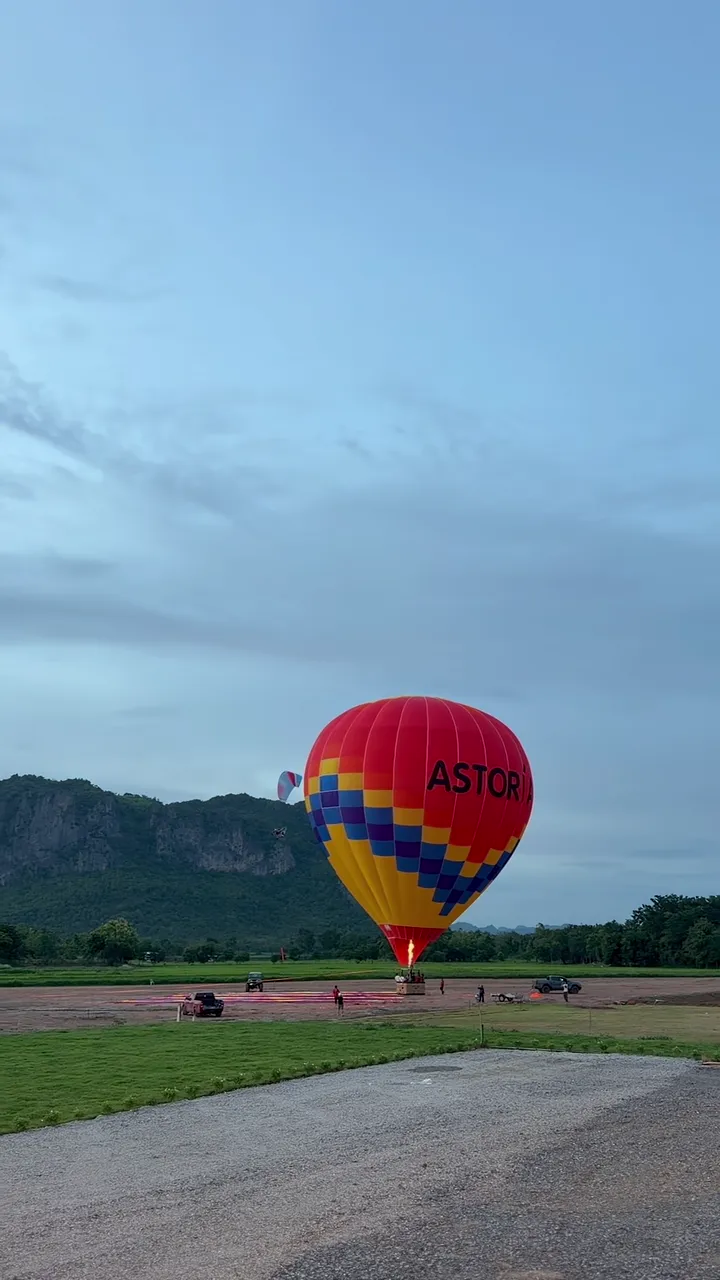 บอลลูนลายธงของ Astoria Airfield จุดหัวเผาเตรียมขึ้นบินบนลานบิน มีแนวเขาเขียวเป็นฉากหลัง